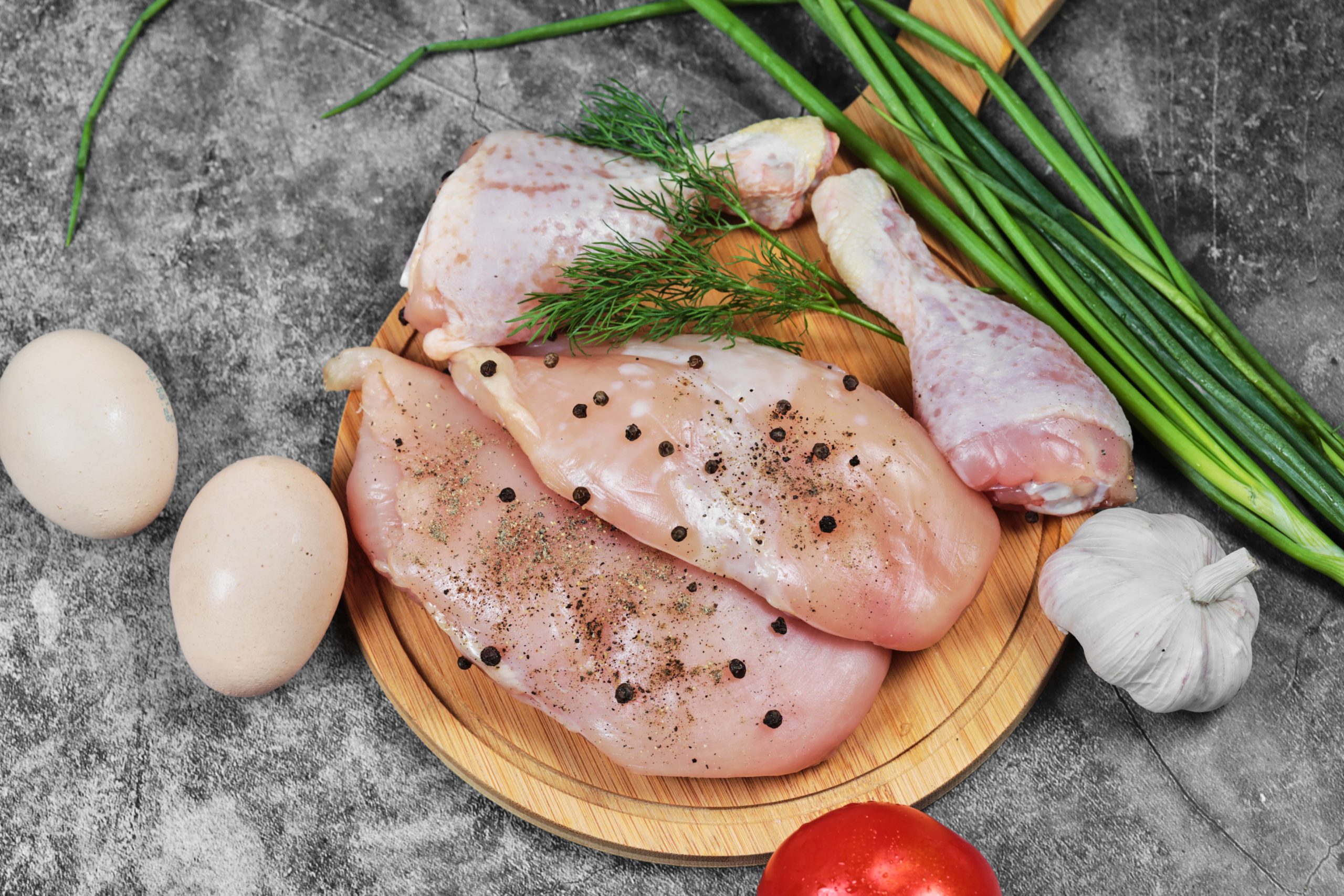 raw-chicken-fillet-and-legs-on-wooden-plate-with-fresh-vegetables-min